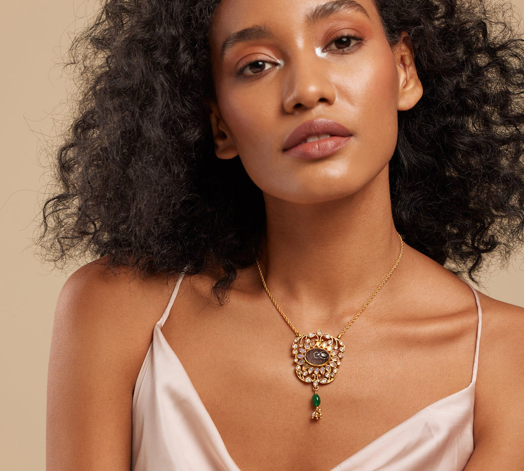 A woman wearing a grey floral semi-precious stone necklace with gold accents.