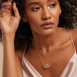 A woman wearing a semi-precious stone necklace with a gold chain and floral design pendant.