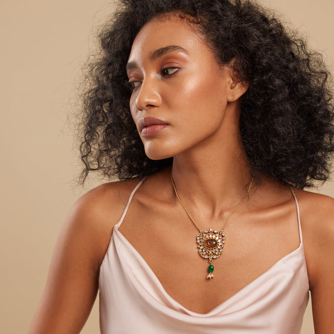 A person wearing a brown floral design necklace with semi-precious stones.