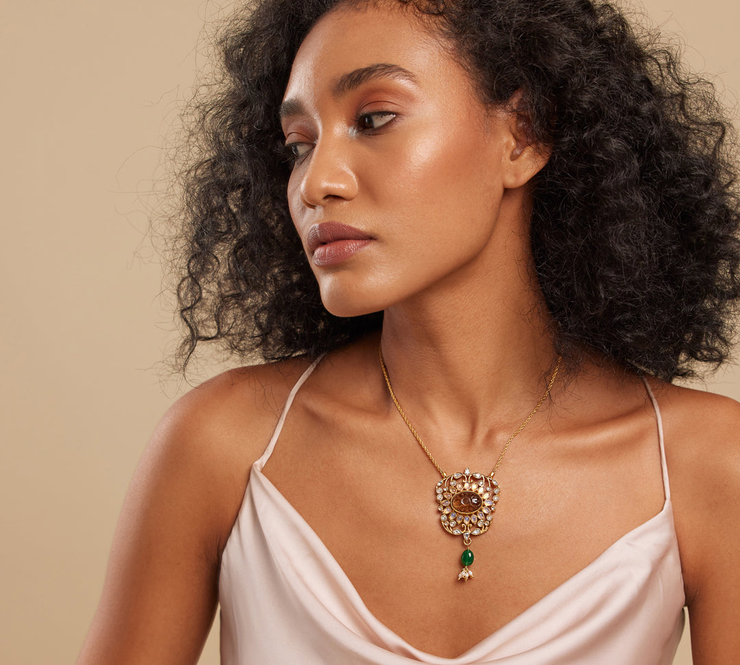 A person wearing a brown floral design necklace with semi-precious stones.