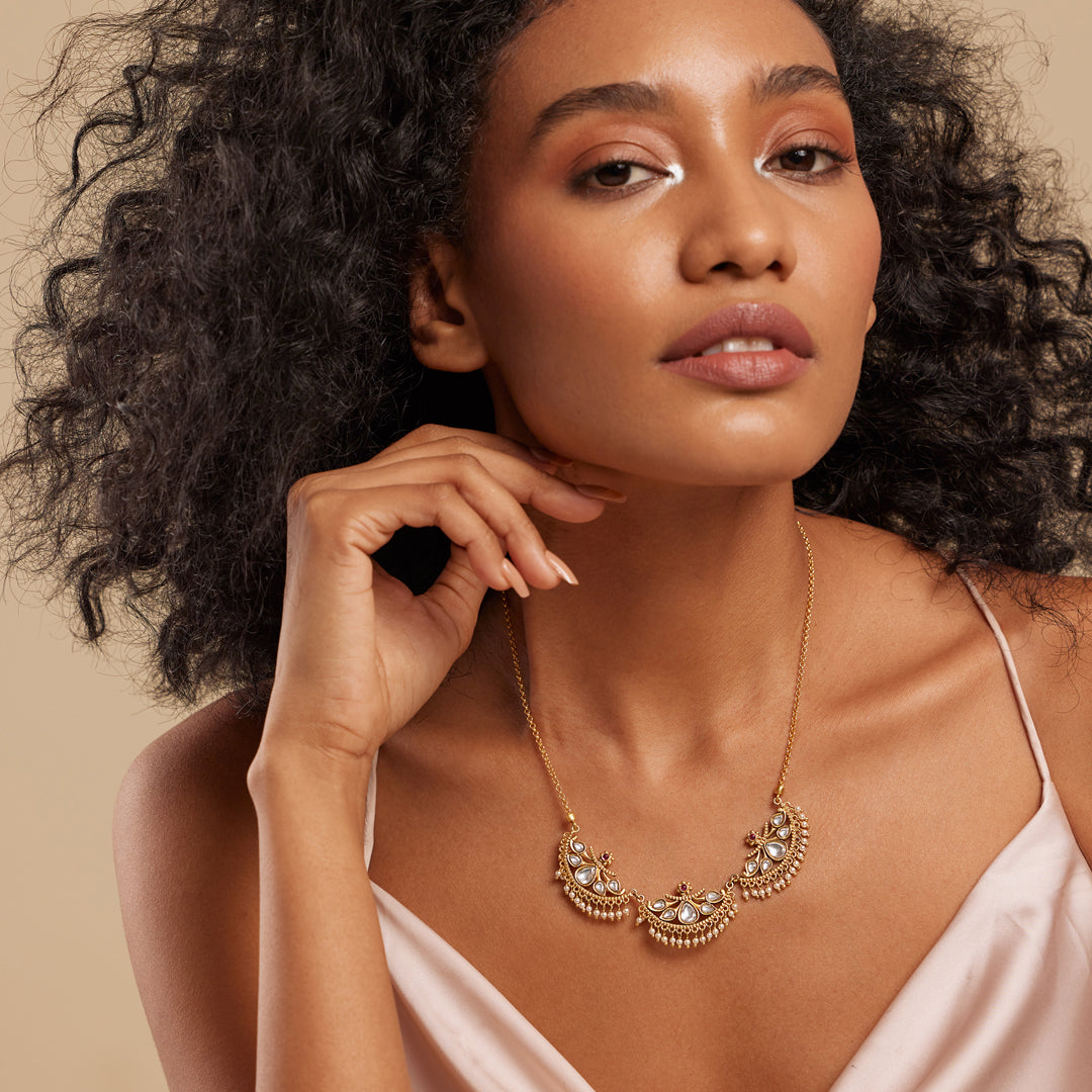 A woman wearing a semi-precious stone necklace with a gold-colored crescent design.