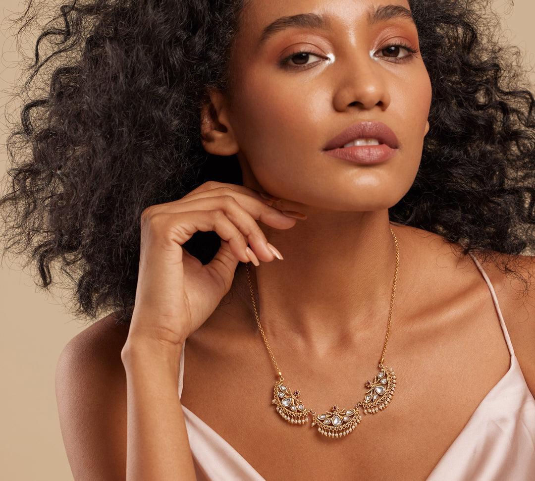 A woman wearing a semi-precious stone necklace with a gold-colored crescent design.