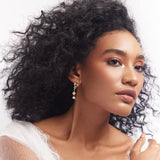 A woman featuring a pair of pastel petite drop earrings with stone embellishments.